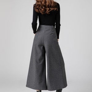 Pu&ograve; includere: Pantaloni grigi a gamba larga e vita alta con un maglione nero a collo alto.