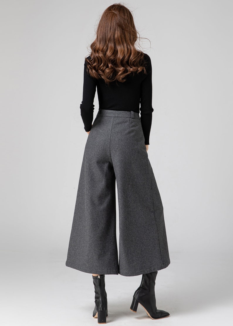 Pu&ograve; includere: Pantaloni grigi a gamba larga e vita alta con un maglione nero a collo alto.