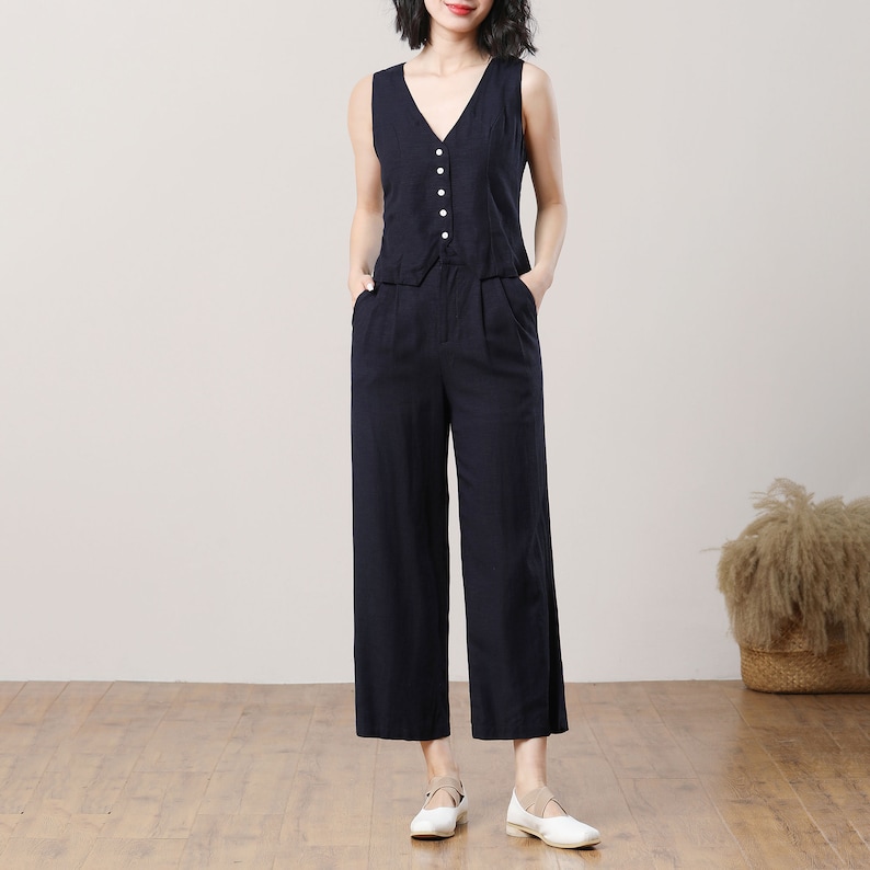 May include: A sleeveless black linen top with a v-neck and button closure, paired with wide-leg black linen trousers.