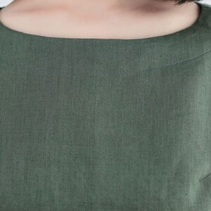May include: Close-up of a green linen dress with a round neckline.