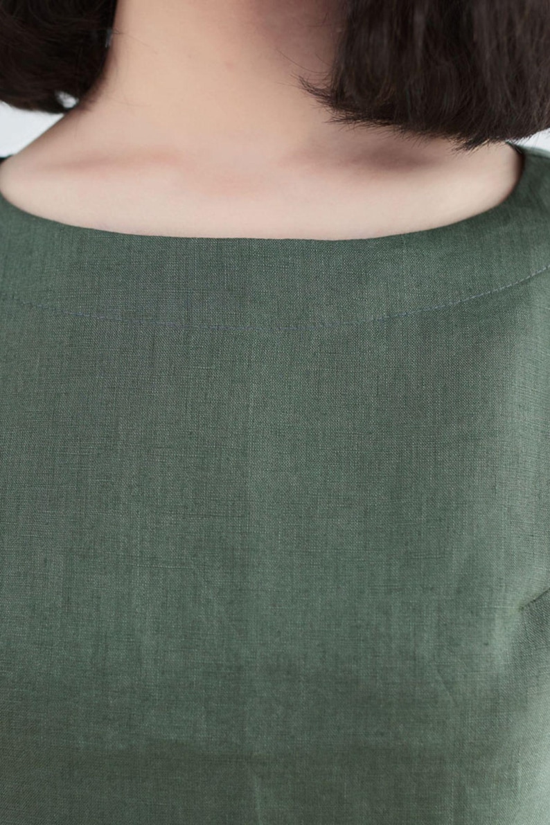 May include: Close-up of a green linen dress with a round neckline.