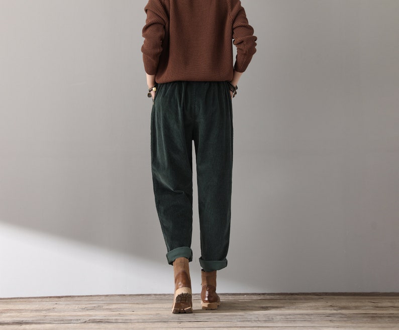 May include: A pair of dark green corduroy pants with a wide leg and a relaxed fit. The pants have a drawstring waistband and are cuffed at the ankles.