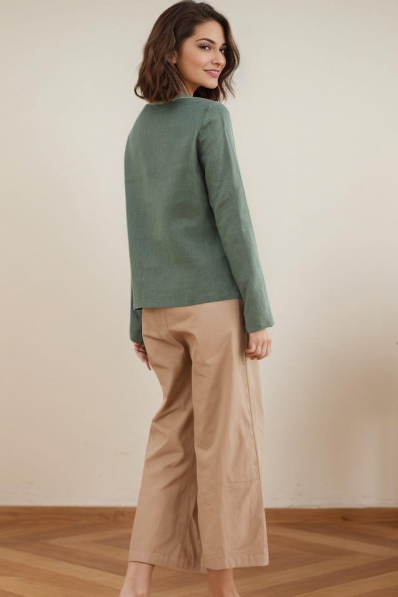 May include: A woman wearing a long-sleeved, sage green shirt and beige wide-leg pants.