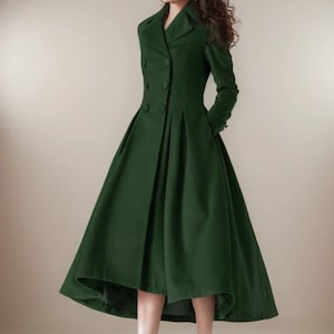 Puede incluir: Un abrigo largo verde bosque con dise&ntilde;o de doble botonadura y falda acampanada. El abrigo presenta un cuello con solapas cl&aacute;sico y se combina con botines negros. Un sombrero negro completa el conjunto.