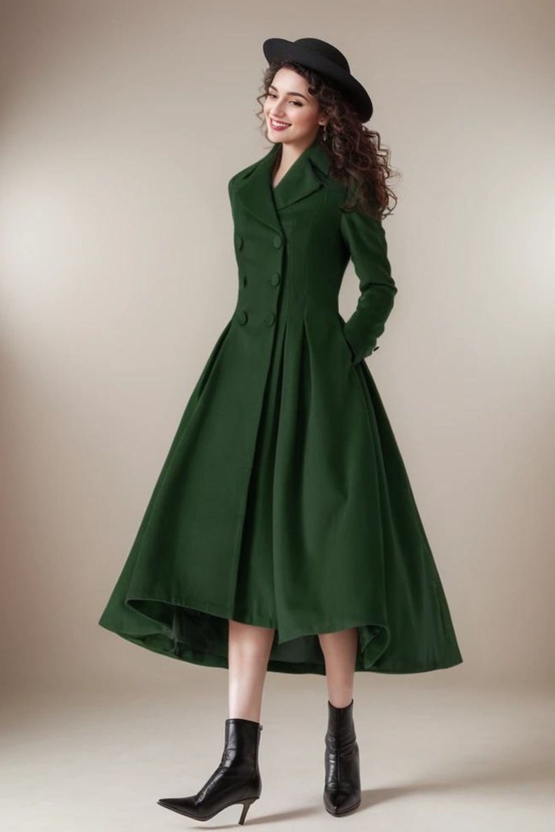 Puede incluir: Un abrigo largo verde bosque con dise&ntilde;o de doble botonadura y falda acampanada. El abrigo presenta un cuello con solapas cl&aacute;sico y se combina con botines negros. Un sombrero negro completa el conjunto.