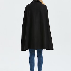 May include: A black cape with a collar, worn over blue jeans and black ankle boots.