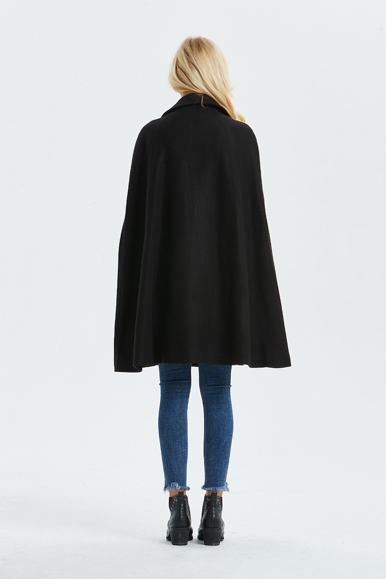 May include: A black cape with a collar, worn over blue jeans and black ankle boots.