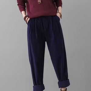 May include: Dark blue corduroy pants with a wide leg and a cuffed hem. The pants have a relaxed fit and are made of a soft, comfortable fabric.