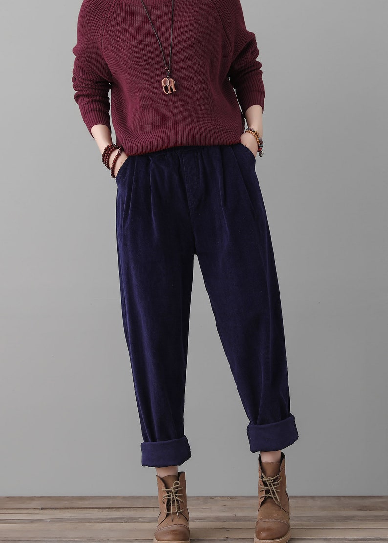 May include: Dark blue corduroy pants with a wide leg and a cuffed hem. The pants have a relaxed fit and are made of a soft, comfortable fabric.