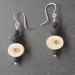 Może przedstawiać: Para srebrnych kolczyków wiszących z czarnymi koralikami z lawy wulkanicznej i drewnianym dyskiem.