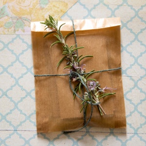 May include: A brown paper package tied with twine and decorated with a sprig of rosemary.