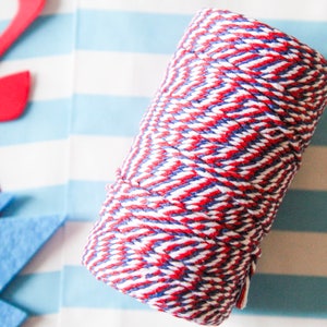 Pu&ograve; includere: Un rotolo di spago da fornaio rosso, bianco e blu. Lo spago &egrave; avvolto strettamente e presenta un motivo a righe.