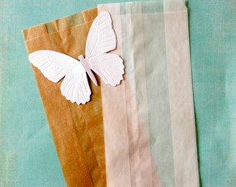 Könnte beinhalten: Ein weißer Papier-Schmetterlingsausschnitt auf einer braunen Papiertüte mit einer durchsichtigen Cellophantüte mit weißen Streifen oben.