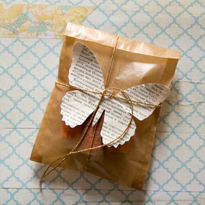 May include: A brown paper package tied with twine and decorated with a butterfly made from pages of a book. The butterfly has gold accents and the text on the pages is in Russian.