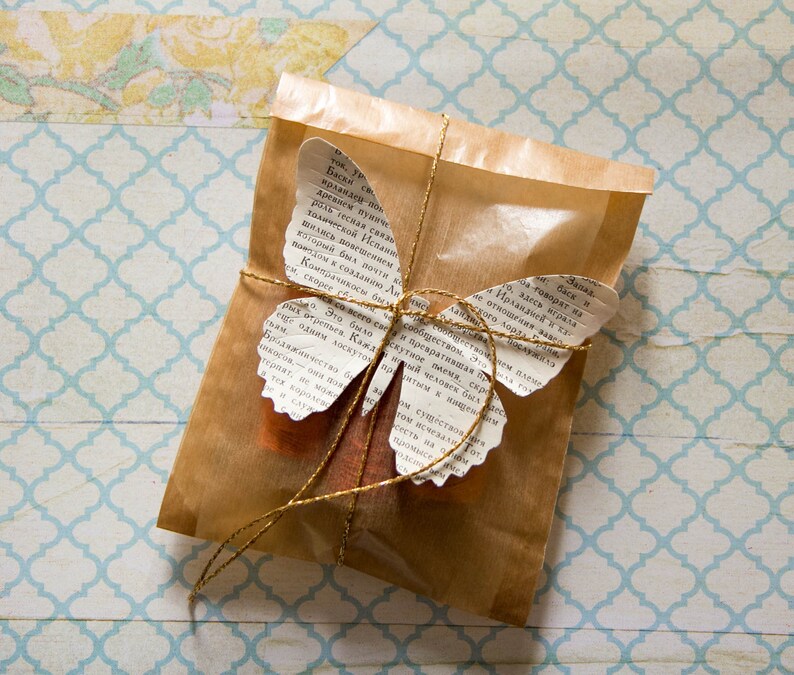May include: A brown paper package tied with twine and decorated with a butterfly made from pages of a book. The butterfly has gold accents and the text on the pages is in Russian.
