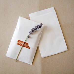 May include: Two white paper envelopes with a sprig of lavender and a brown patterned washi tape on one envelope.