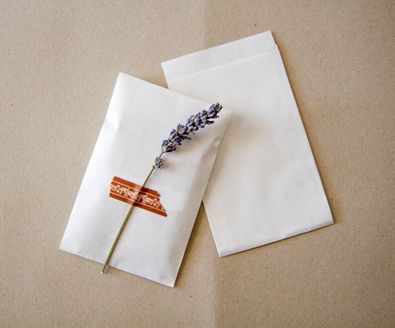 May include: Two white paper envelopes with a sprig of lavender and a brown patterned washi tape on one envelope.