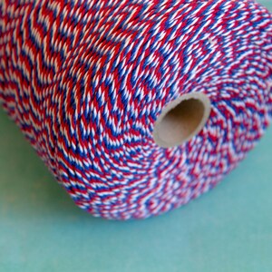 Pu&ograve; includere: Un rotolo di spago da fornaio rosso, bianco e blu. Lo spago &egrave; avvolto attorno a un nucleo di cartone.