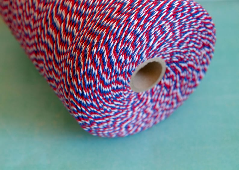 Pu&ograve; includere: Un rotolo di spago da fornaio rosso, bianco e blu. Lo spago &egrave; avvolto attorno a un nucleo di cartone.