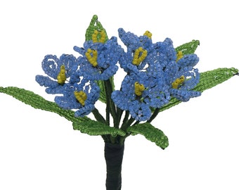 May include: A bouquet of blue and yellow beaded flowers with green leaves. The flowers are made of small beads and are arranged in a cluster. The leaves are also made of beads and are arranged around the flowers.