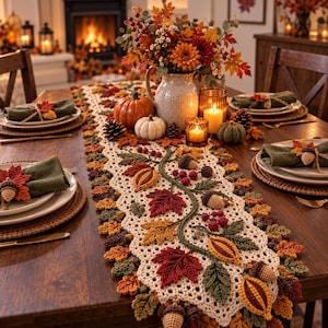 May include: A cream-colored crochet table runner featuring an intricate pattern of autumn leaves, acorns, and berries in shades of red, orange, yellow, and green. The runner is displayed on a wooden table with matching napkins and seasonal decor.