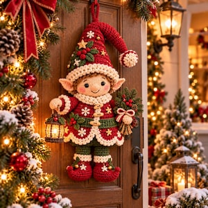 Könnte beinhalten: Ein gehäkelter Weihnachts-Elf als Wandbehang aus rotem, grünem und cremefarbenem Garn. Der Elf trägt eine spitze Mütze, einen Mantel mit Holzknebelknöpfen und Schneeflockenmuster. Er hält eine kleine, beleuchtete Laterne und ein Bündel Tannengrün.