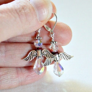 May include: Silver angel wing earrings with clear crystal beads and red accents.
