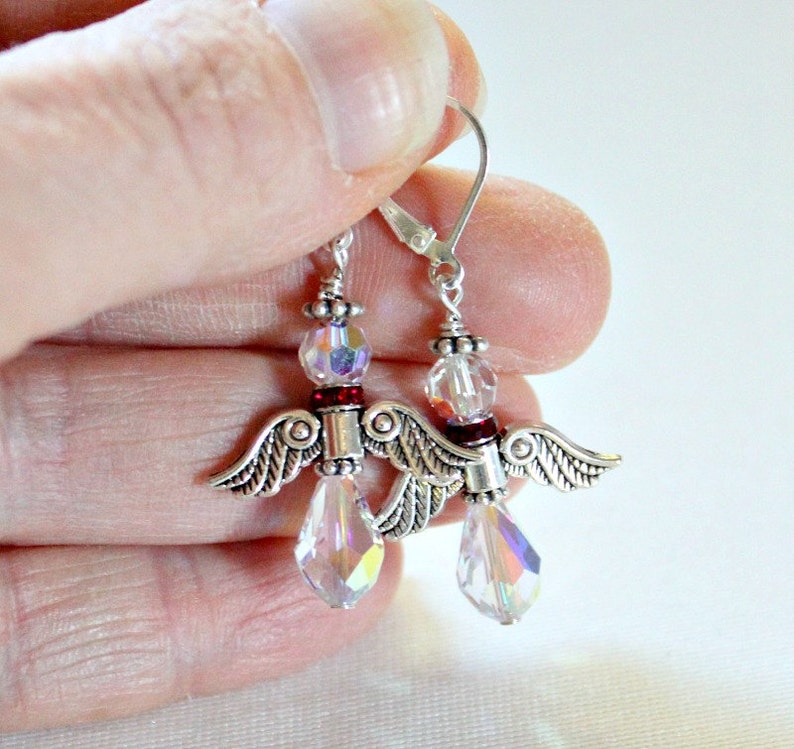 May include: Silver angel wing earrings with clear crystal beads and red accents.