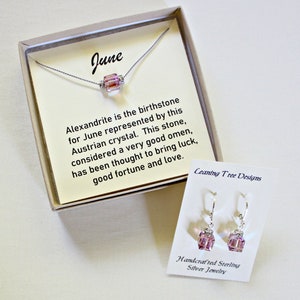 May include: A gift box containing a silver necklace with a pink alexandrite crystal pendant and a pair of matching earrings. The box includes a card that reads "June" and describes the alexandrite as the birthstone for June, considered a good omen to bring luck, good fortune, and love. The card also includes the text "Ceaning Tree Designs". The earrings are labeled "Handcrafted Sterling Silver Jewelry".