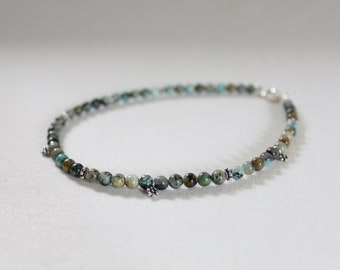 May include: A turquoise and silver beaded bracelet with small silver charms.
