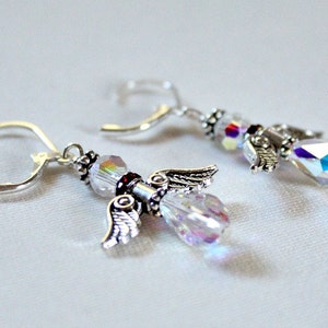 May include: A pair of silver angel wing earrings with clear iridescent crystal beads and a small red bead accent.