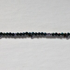 May include: A green and silver beaded bracelet with small silver charms.