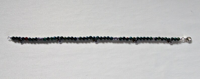 May include: A green and silver beaded bracelet with small silver charms.