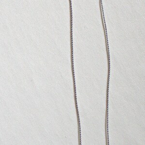 May include: A silver chain necklace with a small, iridescent, rectangular crystal pendant. The pendant is surrounded by two silver rings with small clear crystals. The necklace is shown next to a US penny for size comparison.
