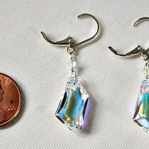 May include: A pair of silver dangle earrings with iridescent crystal teardrop pendants. The earrings are approximately the size of a US penny.