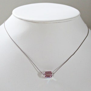 May include: A delicate silver chain necklace with a single, faceted, light purple crystal pendant.