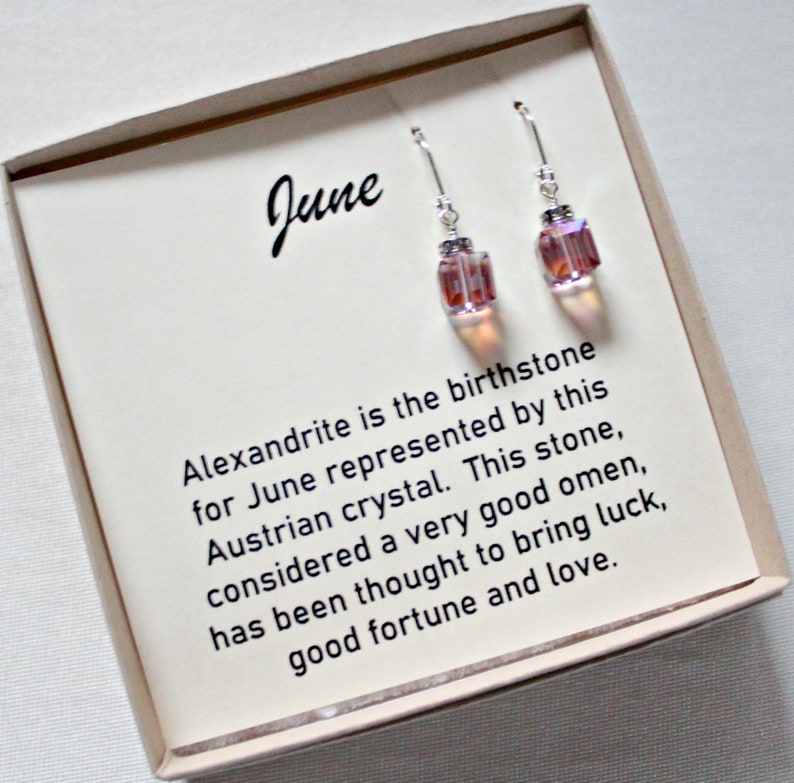 May include: A pair of silver earrings with pink and iridescent crystal stones. The earrings are in a box with a card that reads "June" and explains that alexandrite is the birthstone for June. The card also says that alexandrite is considered a very good omen and is thought to bring luck, good fortune, and love.