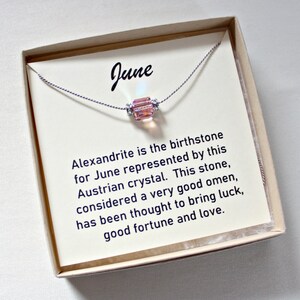 May include: A small box with a white card inside. The card has the word "June" printed on it and a description of Alexandrite, the birthstone for June. A delicate necklace with a pink crystal bead is displayed on the card.