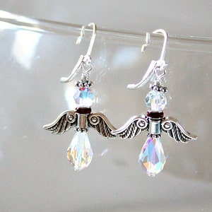 May include: Silver dangle earrings with a crystal teardrop and a silver angel wing charm. The angel wings have a dark red accent.