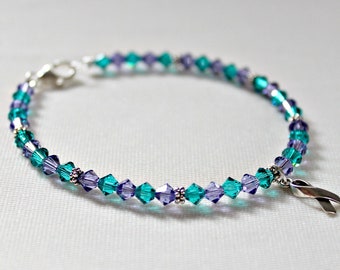 May include: A teal and purple crystal beaded bracelet with a silver ribbon charm.