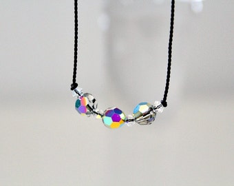 May include: A simple necklace with a black cord and three iridescent crystal beads.