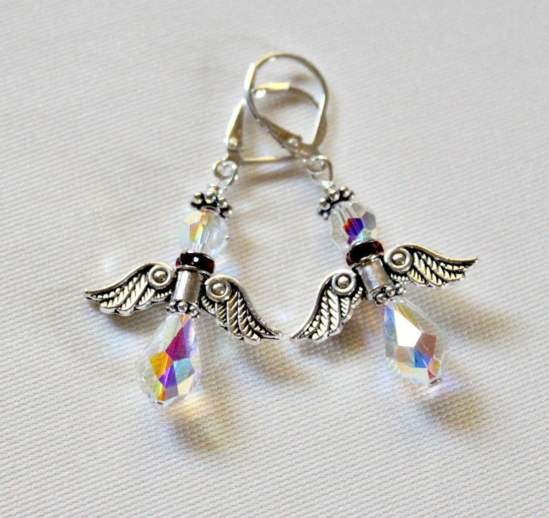 May include: Silver angel wing earrings with iridescent crystal drops and a red accent bead.
