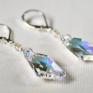 May include: A pair of silver earrings with iridescent crystal teardrop pendants. The earrings have a lever back closure.