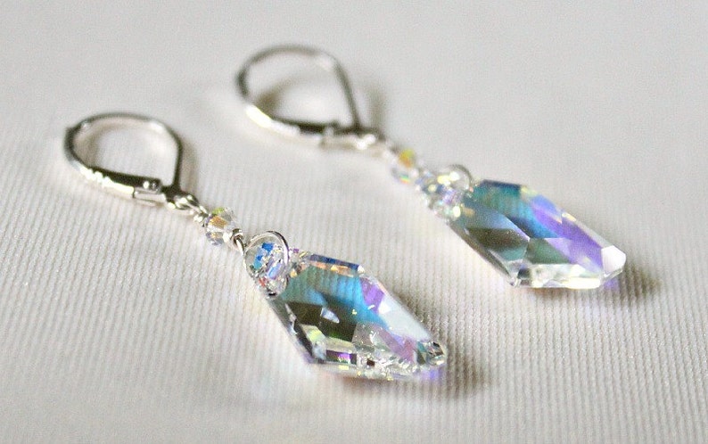 May include: A pair of silver earrings with iridescent crystal teardrop pendants. The earrings have a lever back closure.