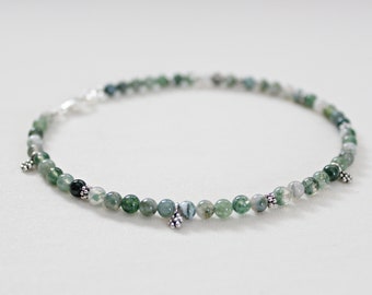 May include: A green agate beaded bracelet with silver accents. The bracelet has a clasp closure and is made with small, round beads.