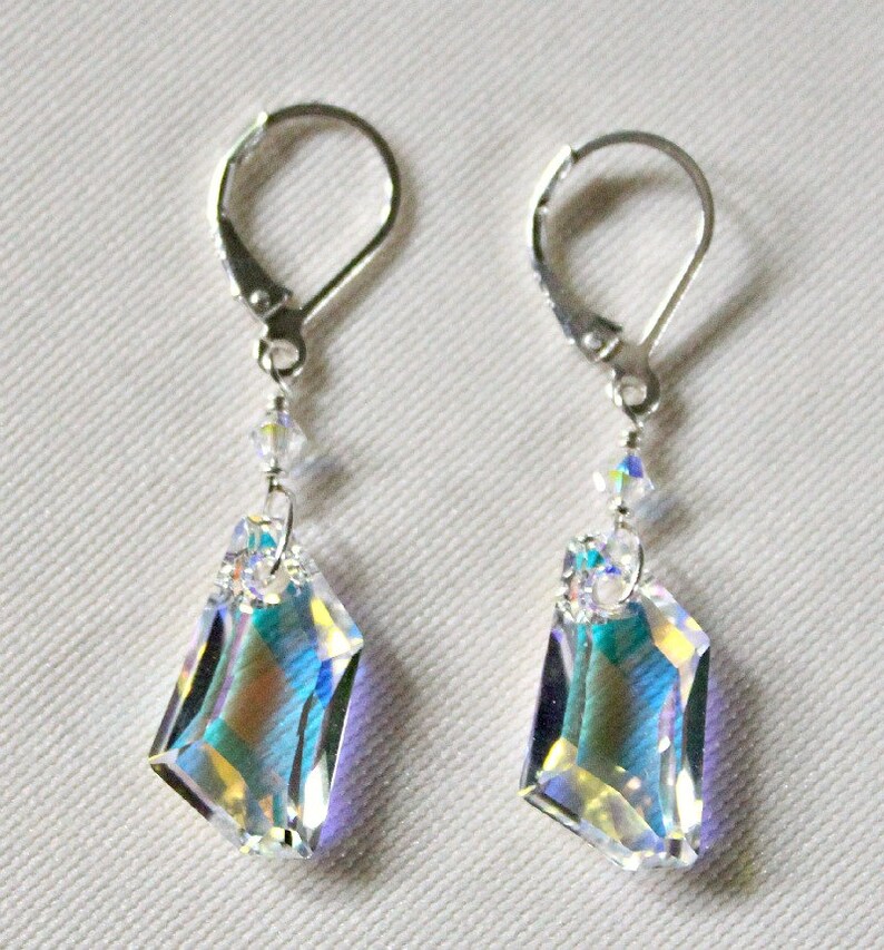 May include: A pair of silver earrings with iridescent crystal drops. The crystals are faceted and have a rainbow effect. The earrings have lever back closures.