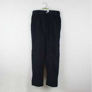 K&ouml;nnte beinhalten: Marineblaue Hose, die an einem Kleiderb&uuml;gel vor wei&szlig;em Hintergrund h&auml;ngt. Die Hose hat einen Knopfverschluss und Taschen. Der Stoff ist einfarbig.