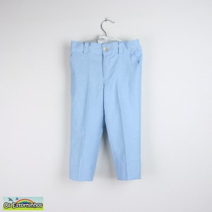 May include: Light blue pants hanging on a white background. The pants have a button closure, belt loops, and pockets. The fabric has a subtle texture. The pants are likely for children.