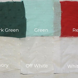 May include: A collection of fabric swatches in various colors, including navy blue, dark green, green, red, pink, blue, ivory, off white, white, and light pink. Each swatch has a textured surface and a label indicating its color.