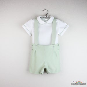 Peut inclure: Ensemble pour bébé composé d'une chemise blanche à manches courtes avec un col rond et une bordure vert menthe. L'ensemble comprend un short vert menthe assorti avec des bretelles et des boutons décoratifs. Idéal pour une occasion spéciale.